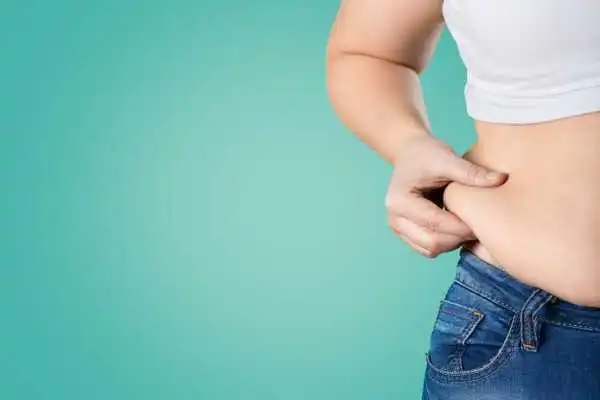 Image of woman pinching her love handles to show weight gain Lichfield